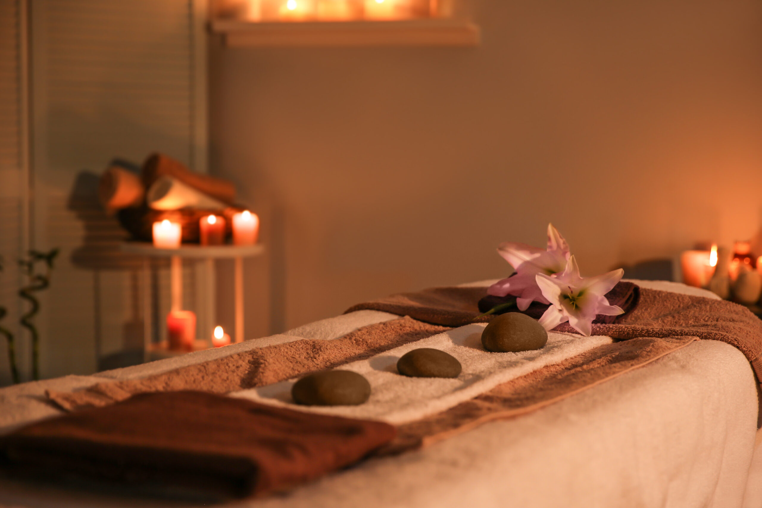 A photo of items you would find at a spa, included soaps, rock salt, bath oils, towels and a burning candle.